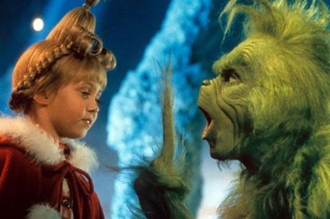 o-grinch Uma criança com cabelos loiros e uma criatura com pelo verde conversando.