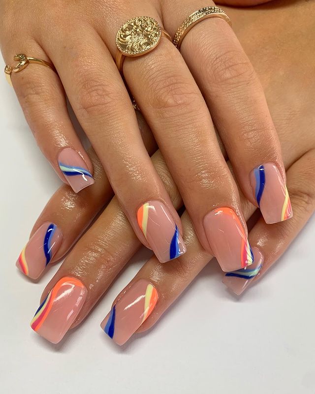 unhas-coloridas-ondas Foto de unhas com um tom de rosa claro e ondas coloridas como decoração.