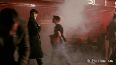 emma-watson Emma de boina preta e sobretudo caminhando por uma estação de trem.