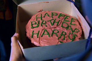 harry-potter (8) Bolo rosa com escritos em verde numa caixa.