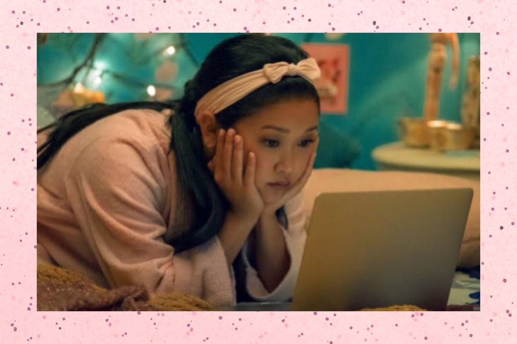 Foto da personagem Lara Jean deitada na cama, mexendo no computador.