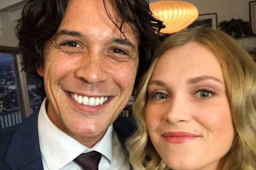 Bob Morley e Eliza Taylor em selfie; ele está sorrindo abertamente e ela está sorrindo levemente com o rosto próximo ao dele