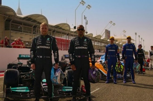 Pilotos frente aos carros em uma pista de corrida.