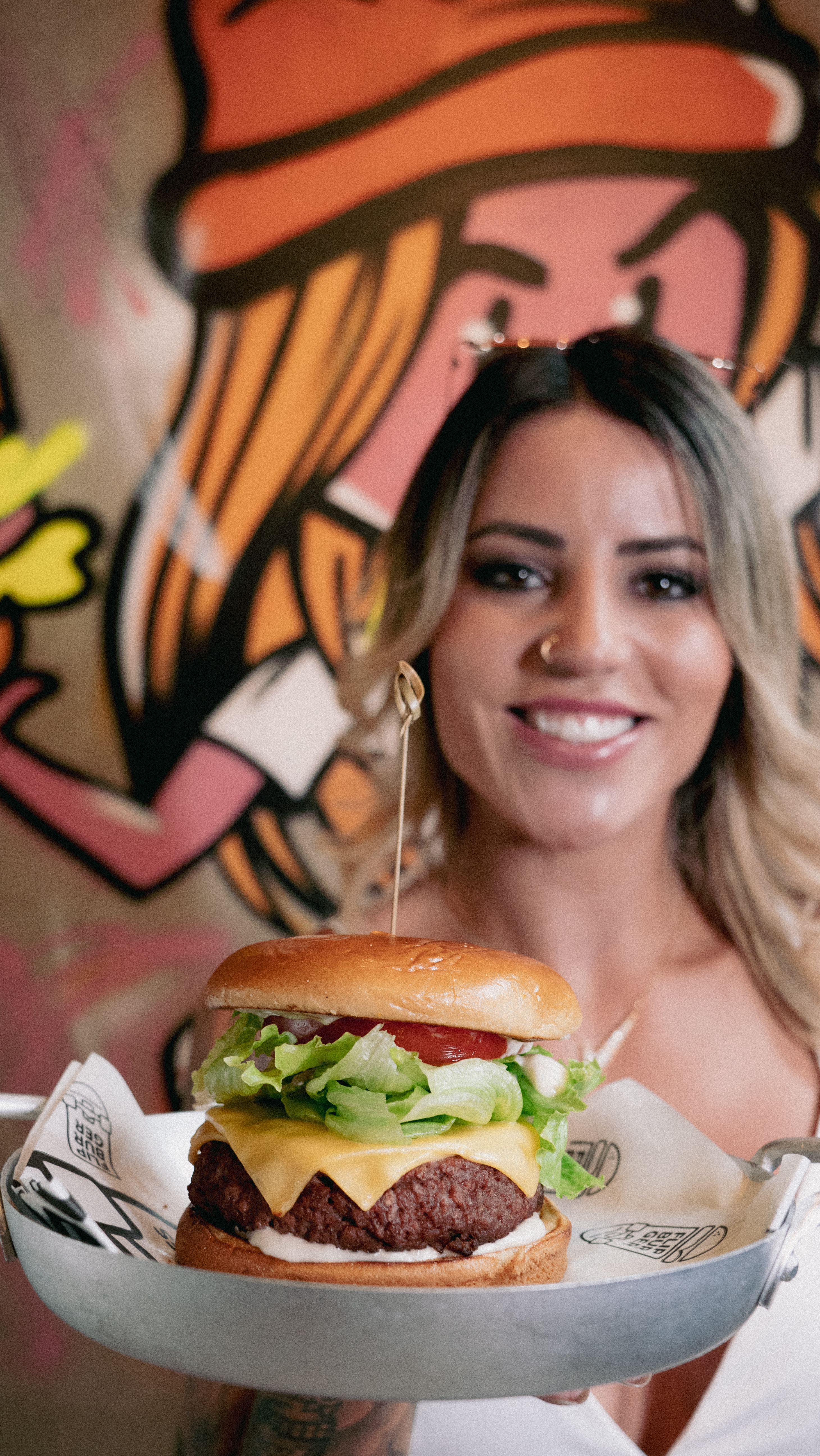 leticia-bufoni-hamburgueria-flip-burger- Leticia Bufoni sorrindo e segurando um hambúrguer em sua hamburgueria