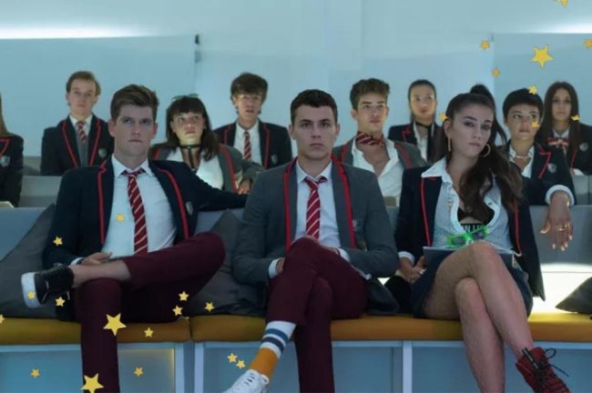 uniforme-elite Guzmán, Ander e Rebeka em cena de Elite; eles estão sentados em um auditório com expressões sérias e uniforme de Las Encinas