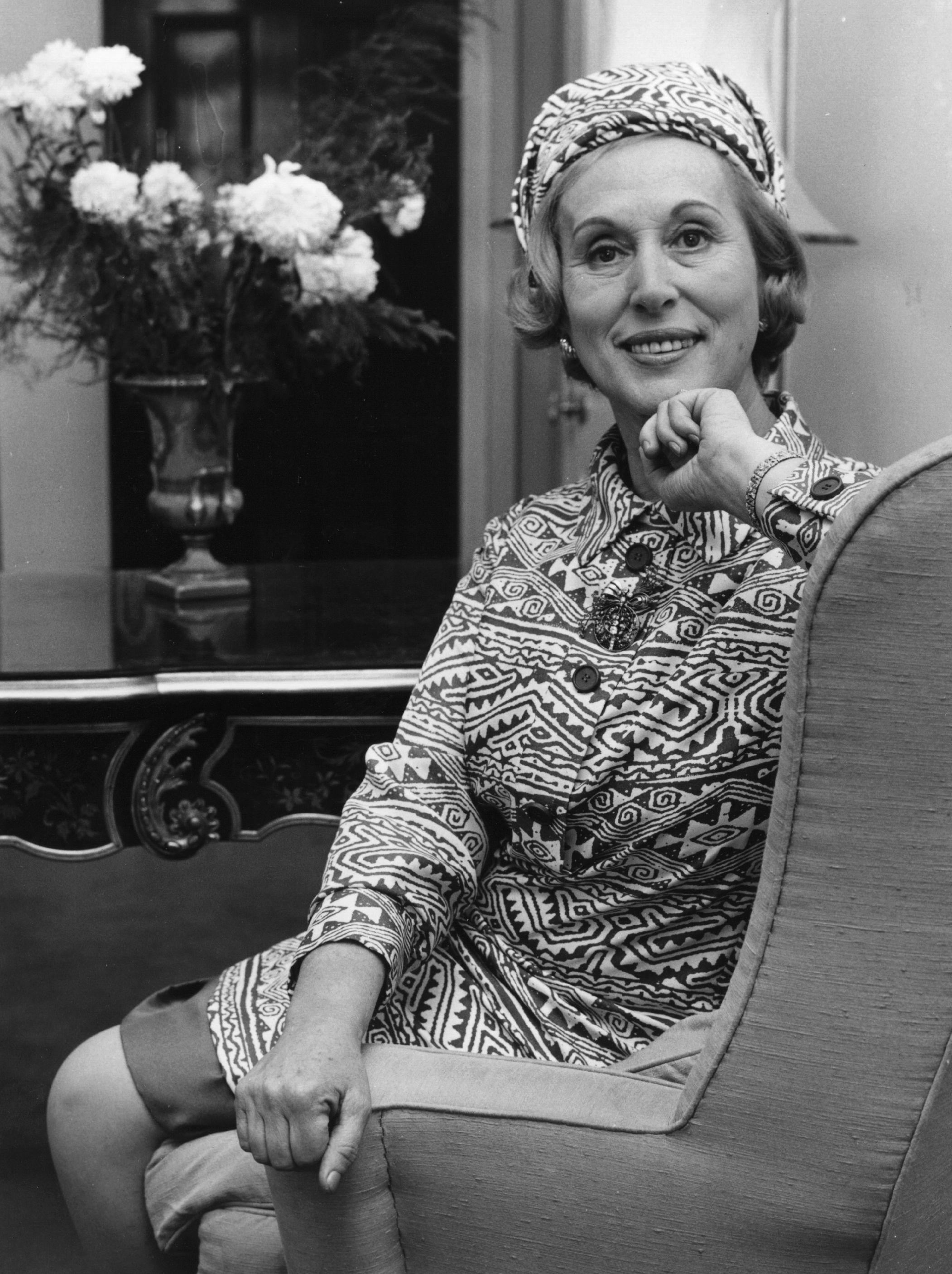 Estee Lauder A empreendedora Estée Lauder sorrindo e olhando para a câmera sentada em uma cadeira
