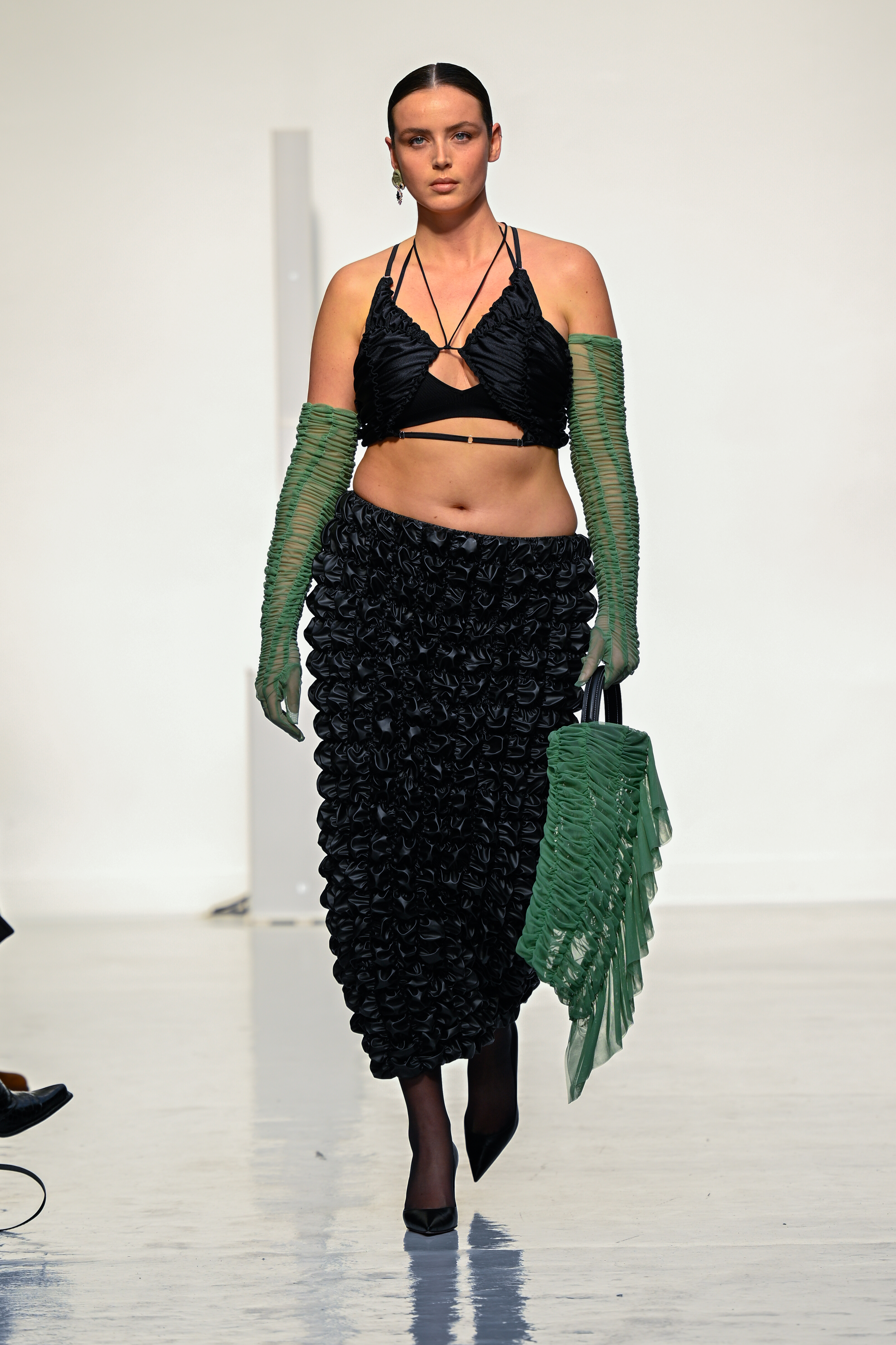 Ester Manas : Runway – Paris Fashion Week – Womenswear F/W 2022-2023 Modelo usando top preto, saia longa preta, luvas verdes e carregando bolsa verde em Desfile de outono-inverno 2022-23 da Ester Manas na semana de moda de Paris