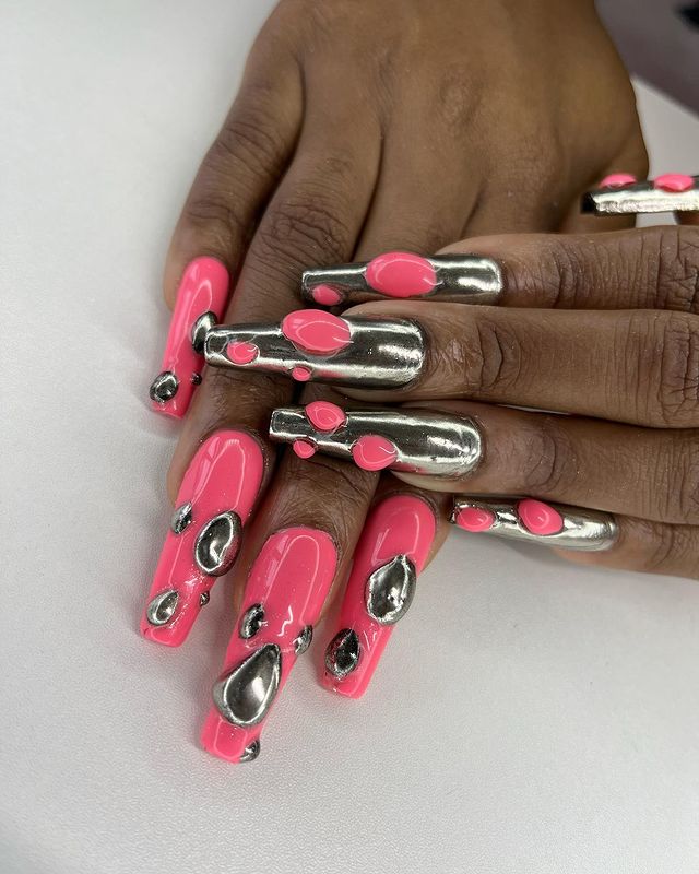 Foto de unhas decoradas com esmalte metalizado e aplicação 3D rosa.