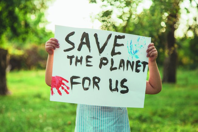 Em três anos, algumas regiões da Terra podem morrer e se tornar inabitáveis Criança segurando um cartaz com os dizeres: