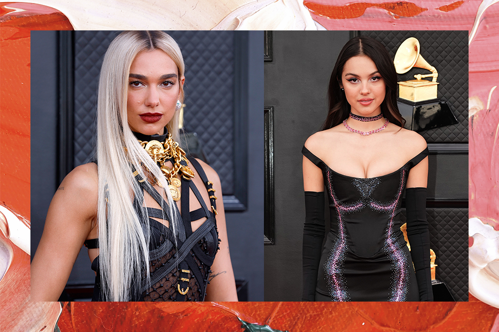 Montagem mostra, de um lado, Dua Lipa usando vestido preto com tiras e muitos detalhes dourados. Olha para a câmera com expressão leve e lábios pintados de vermelho. De outro, Olivia Rodrigo usando vestido preto de cetim com detalhes em brilho rosa. Ela olha em direção à câmera levemente sorrindo. A imagem segue acompanhada de um borda colorida com pinceladas de tinta.