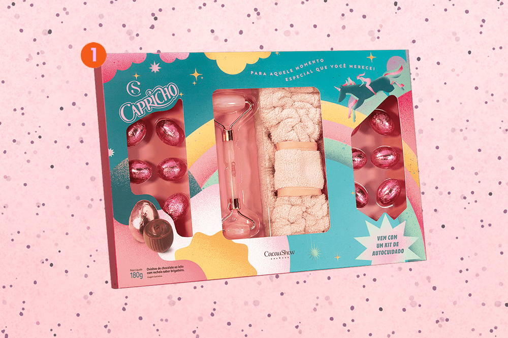kit-de-páscoa-capricho+e-cacau-show Imagem mostra Kit Páscoa da CAPRICHO e Cacau Show com ovinhos de chocolate e itens de skincare em um fundo de textura rosa com bolinhas transparentes espalhadas em nuances de roxo claro e escuro.