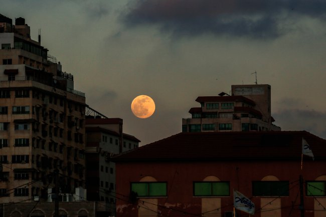 Lua de Sangue surgindo avermelhada por entre edifícios antigos