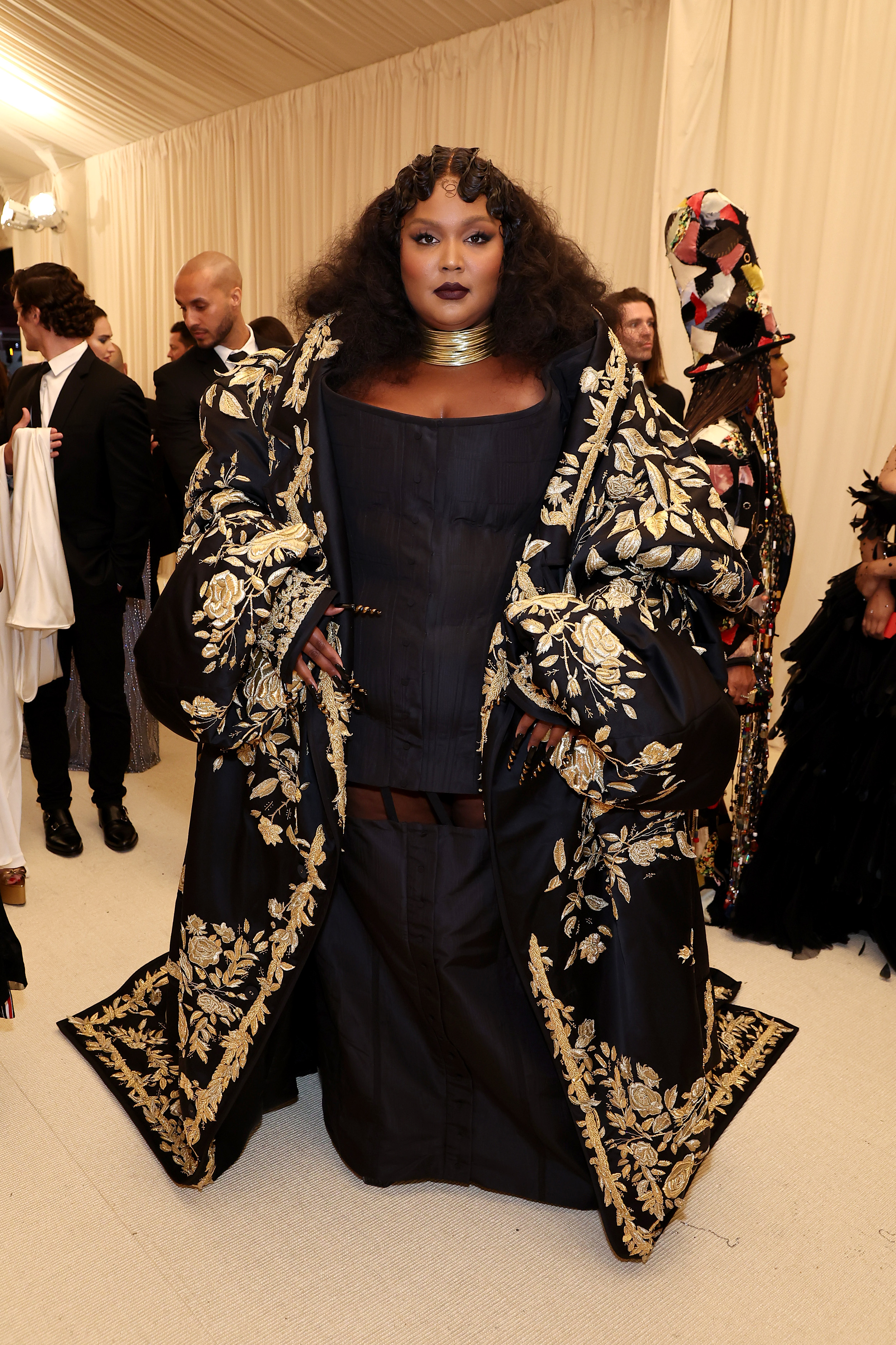 The 2022 Met Gala Celebrating “In America: An Anthology of Fashion” – Red Carpet A imagem mostra Lizzo usando vestido preto e capa com bordado dourado no tapete vermelho do MET Gala 2022, no Metropolitan Museum of Art em 02 de maio de 2022 na cidade de Nova York.