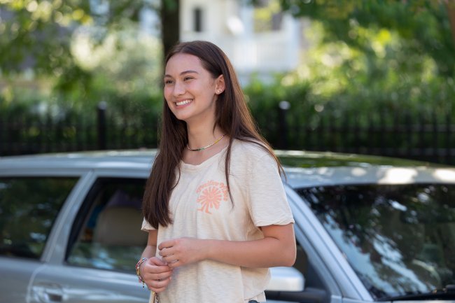 Personagem Belly, de O Verão Que Mudou A Minha Vida sorrindo na frente de um carro