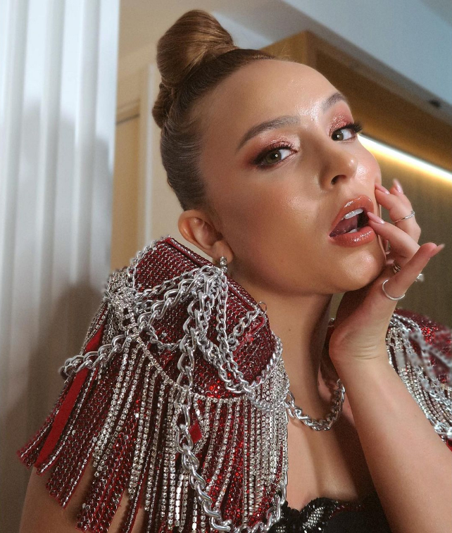 larissa-manoela-maquiagem-sombra-cintilante Larissa Manoela com boca levemente aberta, uma das mãos encostando nos lábios e cabeça levemente inclinada