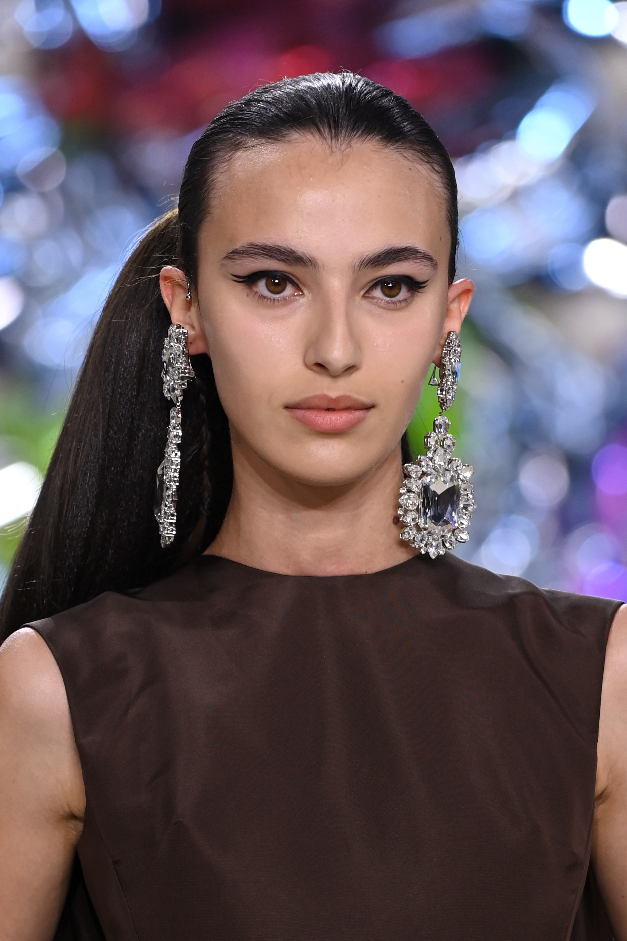 Modelo usando maxibrincos, com expressão facial séria, rabo de cavalo volumoso e a tendência do delineado rabo de peixe no Desfile de outono-inverno 2022-23 da Giambattista Valli na semana de alta-costura em Paris