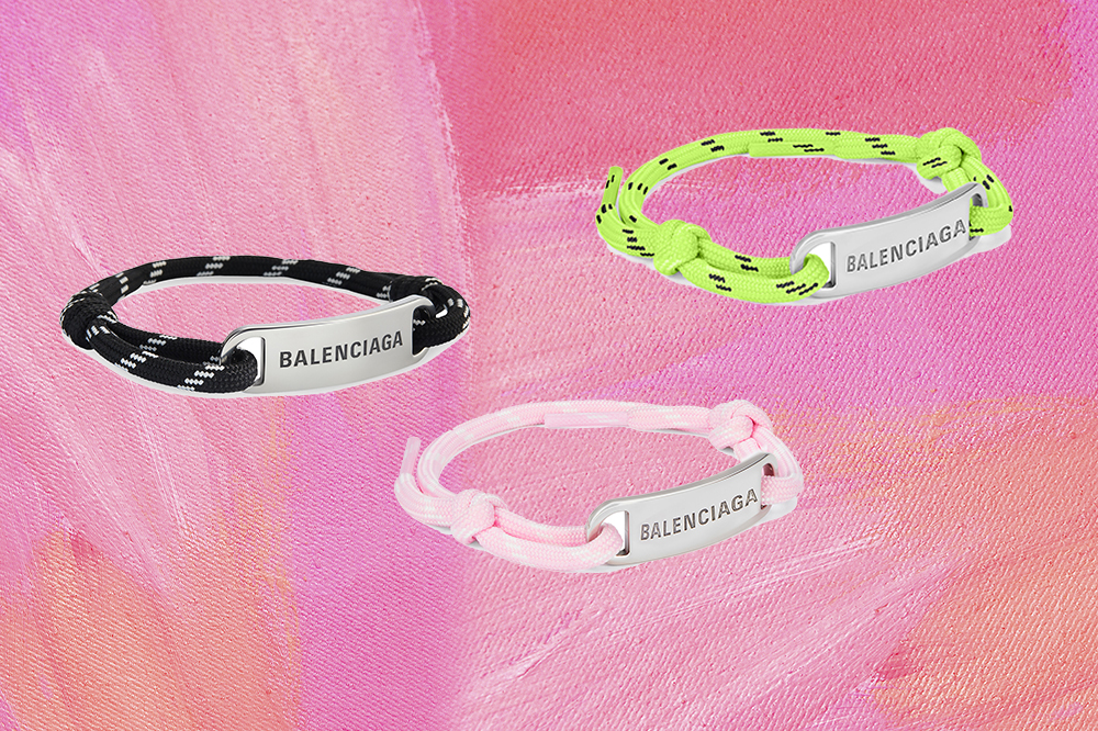balenciaga-pulseiras-cadarço Montagem em fundo rosa com três pulseiras da Balenciaga feitas de cadarço nas cores preto, verde neon e rosa claro