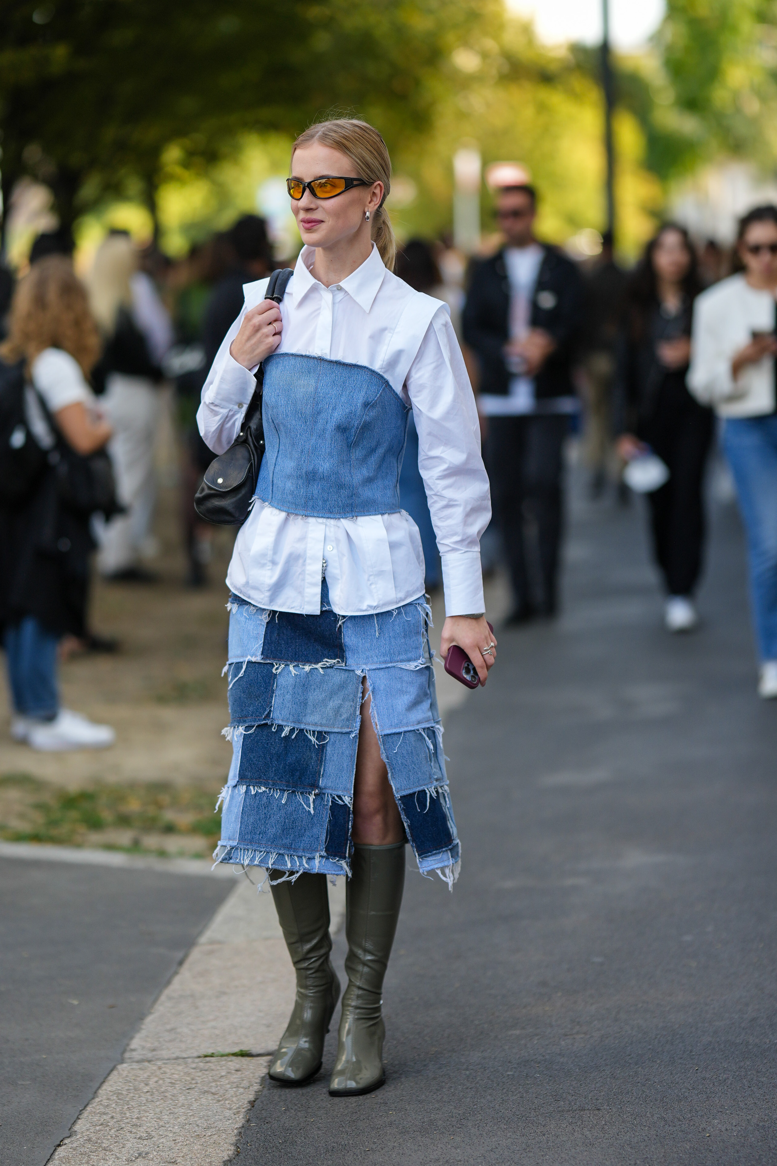 StreetStyle – Day 3 – Milan Fashion Week Womenswear Spring/Summer 2023 Mulher usando camisa branca com top jeans por cima, saia jeans e bota verde no street style da semana de moda de Milão