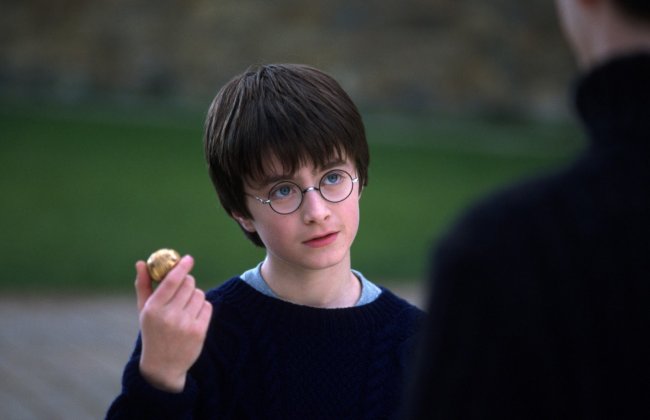 crushes aleatórios (e outros nem tanto) da infância Harry Potter em A Pedra Filosofal, segurando um pomo de ouro