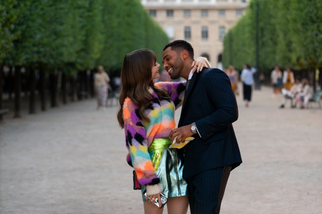 Lily Collins e Lucien Laviscount como Emily e Alfie em cena de Emily em Paris; eles estão abraçados na rua enquanto sorriem com os rostos próximos um do outro