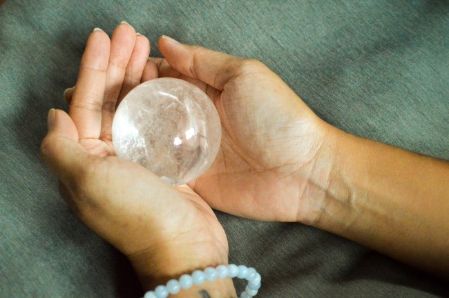 Faxina de fim de ano: veja como eliminar o velho para se abrir para o novo Mãos seguram uma bola de cristal
