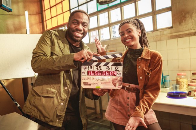 Lázaro Ramos e Gabz segurando claquete de filme e sorrindo