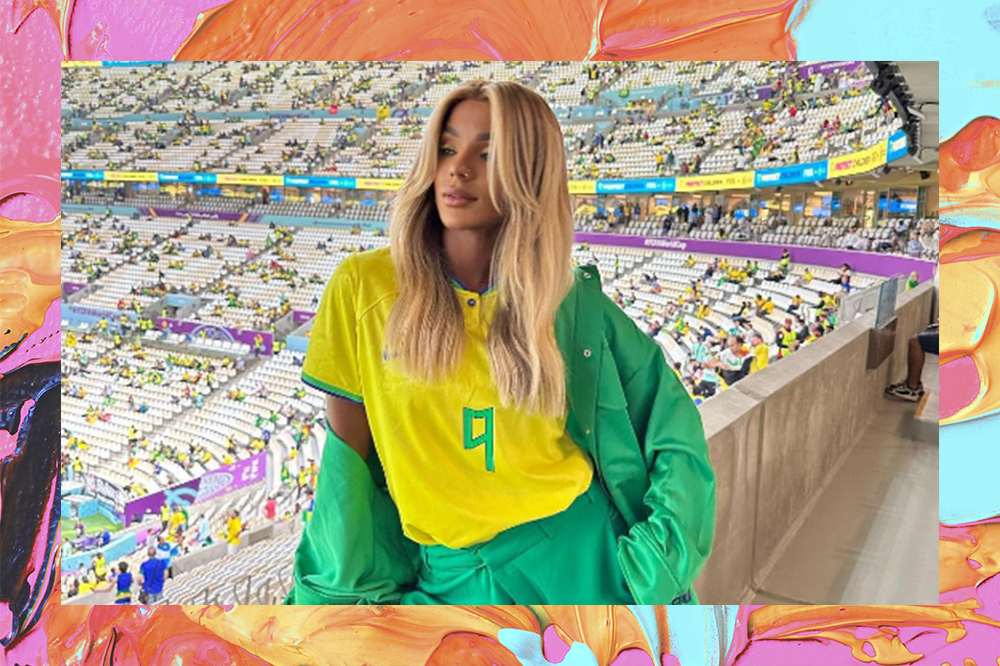 Brunna Gonçalves na Copa do Mundo do Catar 2022 usando camiseta do Brasil e calça verde. Fundo da montagem é laranja, azul e rosa