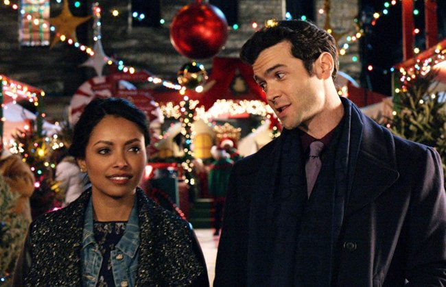 6 filmes natalinos com protagonismo preto Cena do filme O Feitiço do Natal. Uma mulher nergra conversa com um homem branco. Eles vestem roupas de Inverno e estão numa feira de Natal