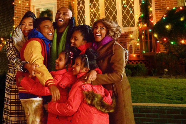 6 filmes natalinos com protagonismo preto Cena do filme O Natal Está no Ar. Uma família negra se abraça em frente a uma casa decorada