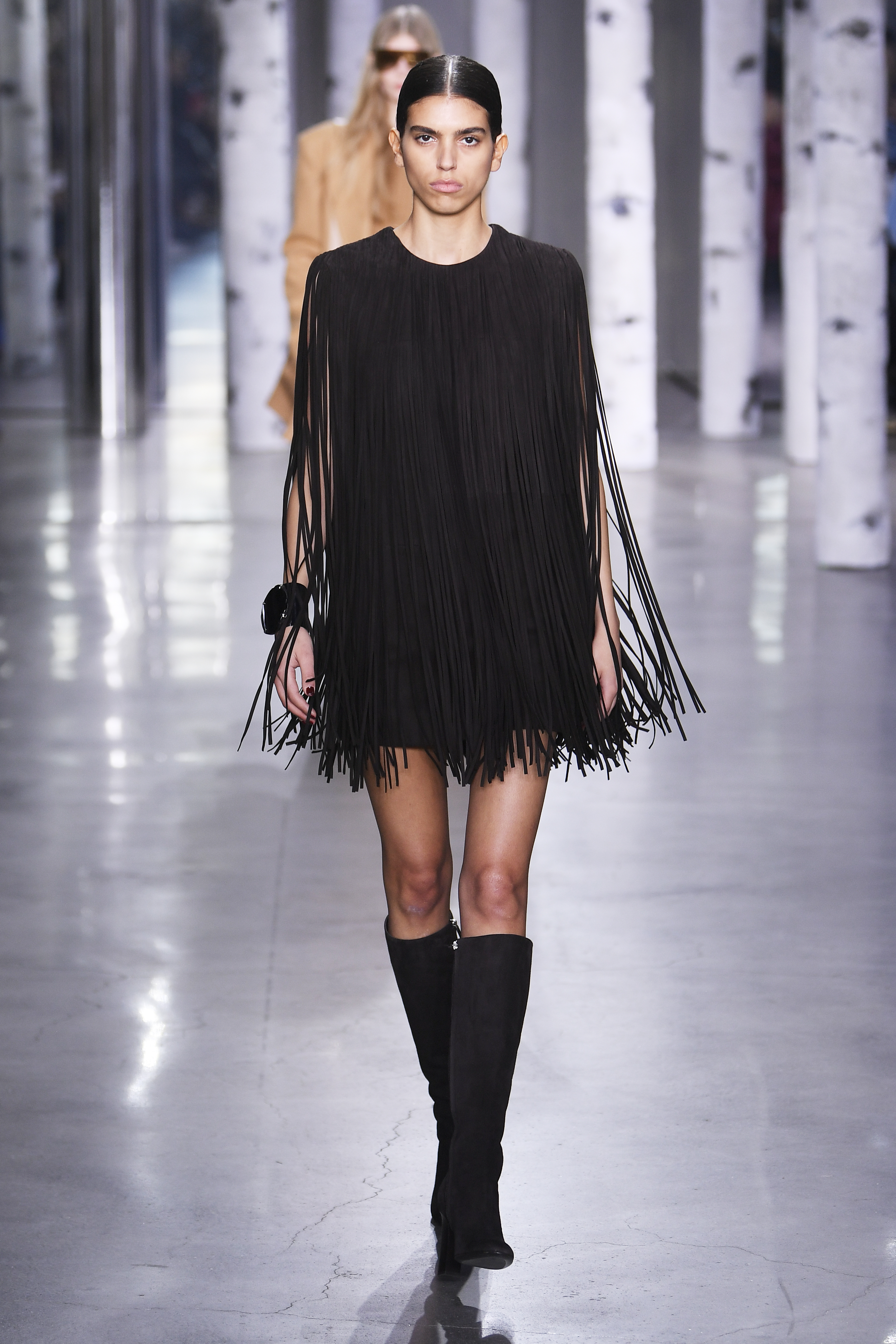 Michael Kors – Fall 2023 – RTW – Runway Desfile de outono-inverno 2023 da Michael Kors na semana de moda de Nova York. Modelo usando vestido preto de franjas e bota até o joelho