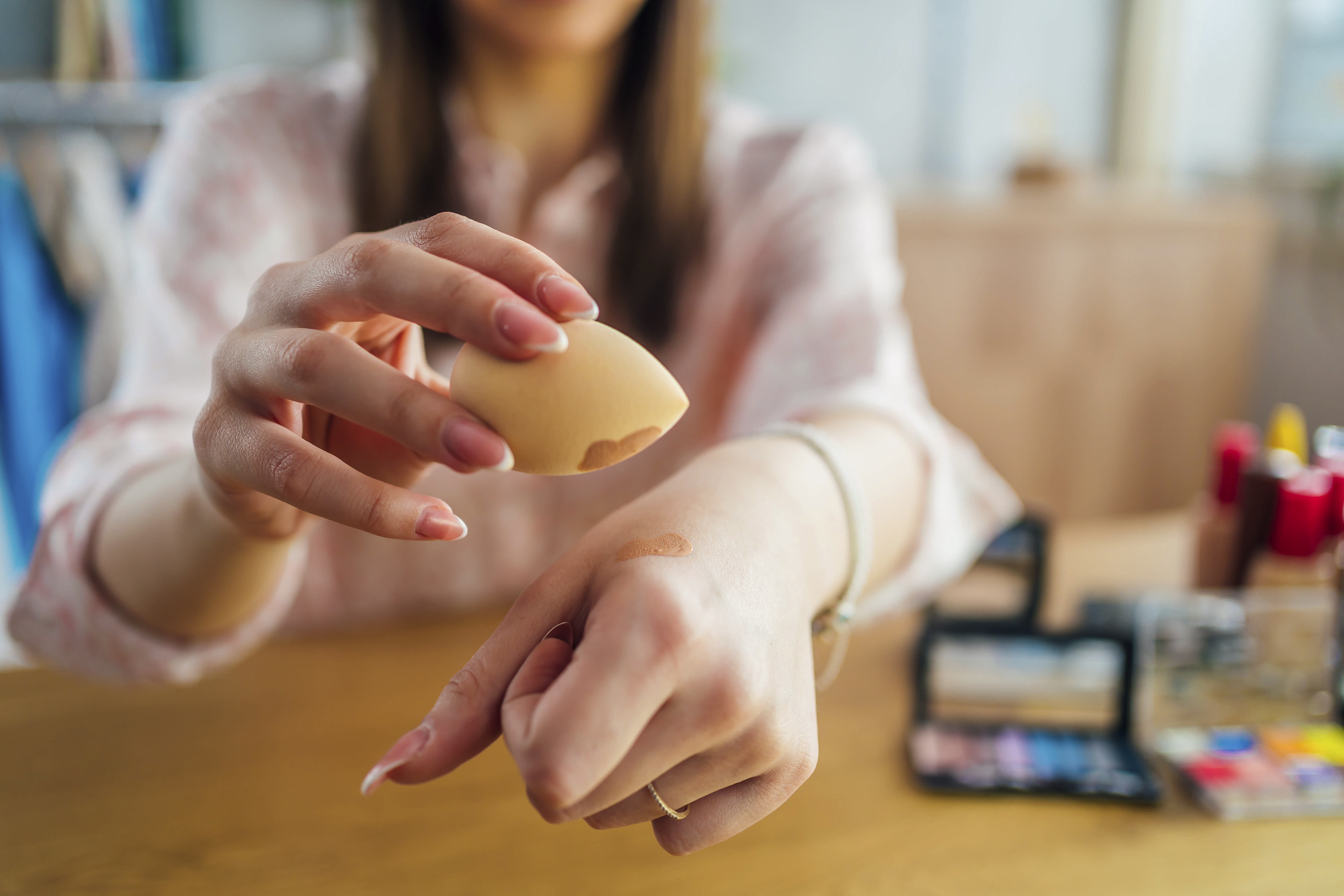 Woman holding beauty blender sponge Mulher segurando uma esponjinha de maquiagem com base em uma das mãos