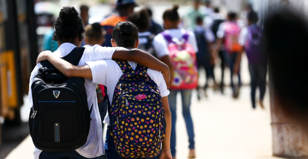 Duas estudantes se abraçam em ambiente escolar