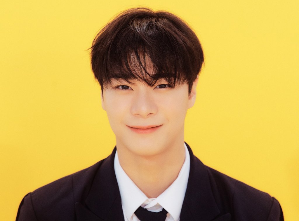 Moonbin, do ASTRO, sorrindo levemente enquanto posa para foto em um fundo amarelo