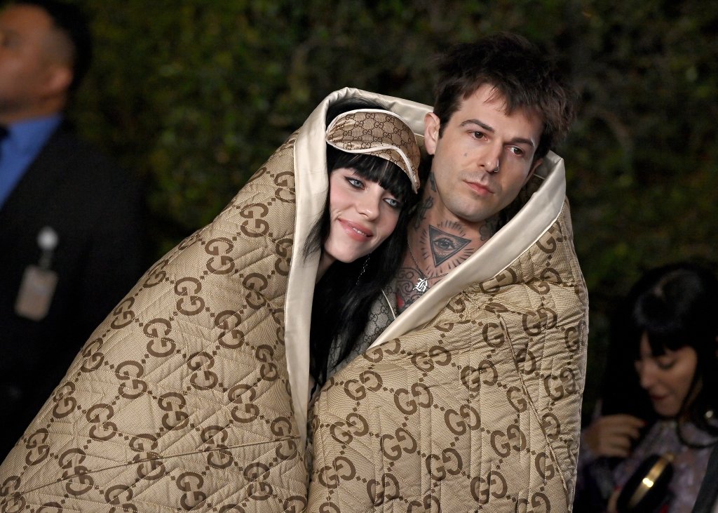 Billie Eilish e Jesse Rutherford no LACMA Art + Film Gala em Los Angeles; eles estão posando para foto no tapete vermelho do evento enquanto dividem um cobertor