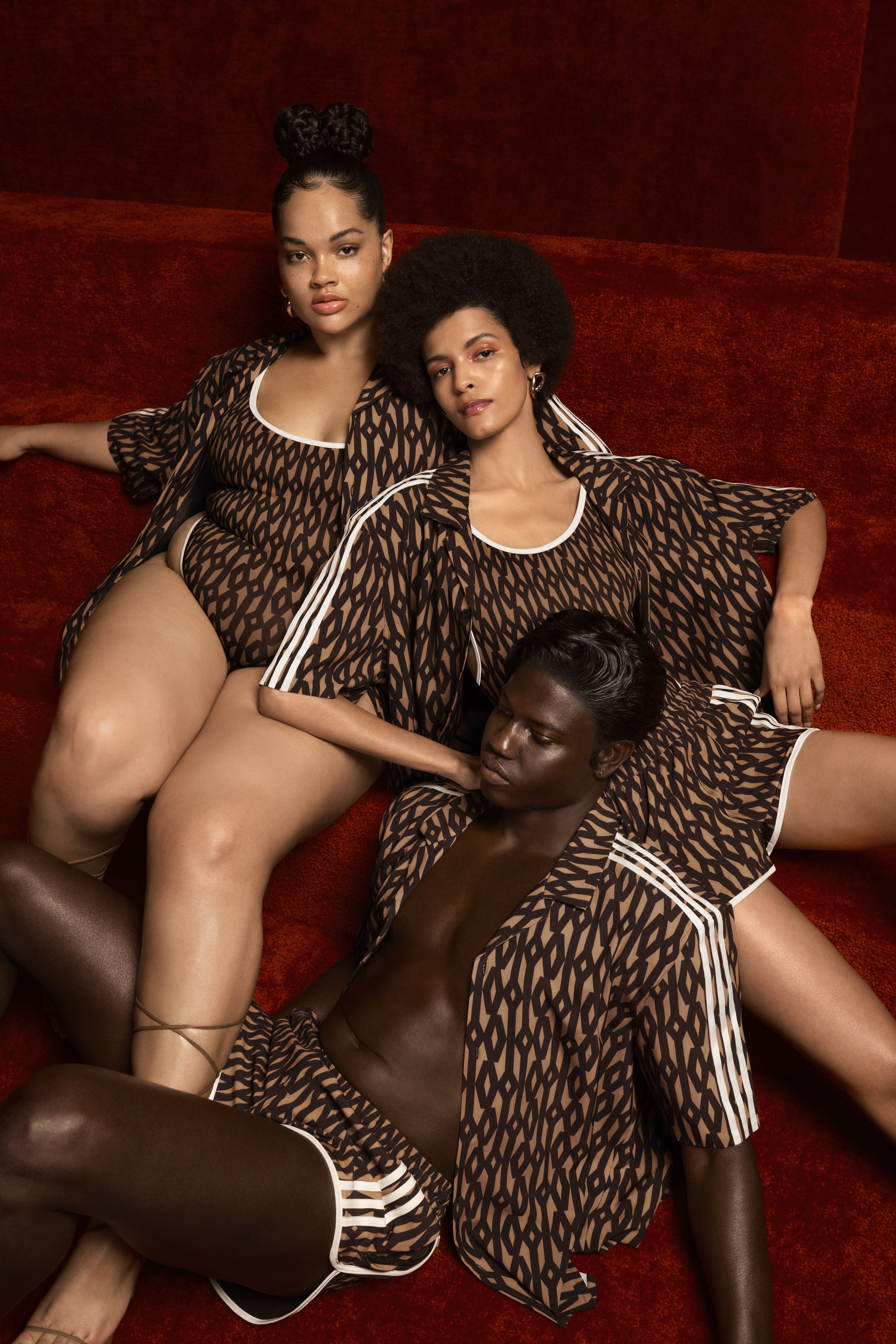monograma-da-ivy-park-em-nova-coleção Na imagem há três modelos com roupas esportivas marrons que têm o monograma da Ivy Park. Uma mulher aparece no canto superior direito, nela está encostada a Laiza de Moura que está sentada no sofá marrom e no chão está um homem que se apoia em Laiza.