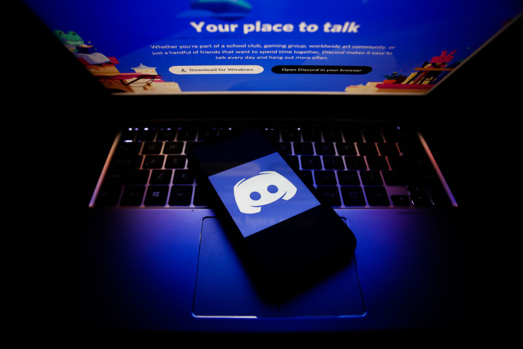 O logotipo do Discord exibido na tela do telefone e o site do Discord exibido na tela do laptop são vistos nesta foto ilustrativa