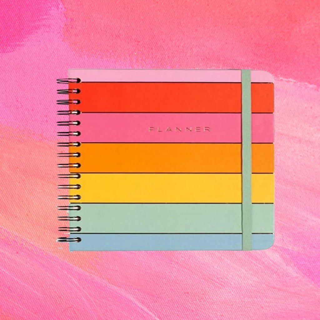 planner (6) Planner com listras em diferentes cores formando um arco-íris; o fundo é uma textura em tons de rosa e branco