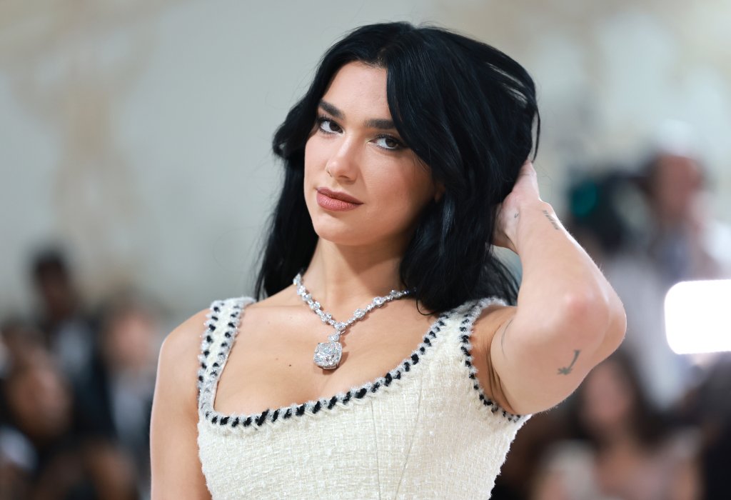 Dua Lipa posando para foto com uma das mãos no cabelo enquanto olha para câmera