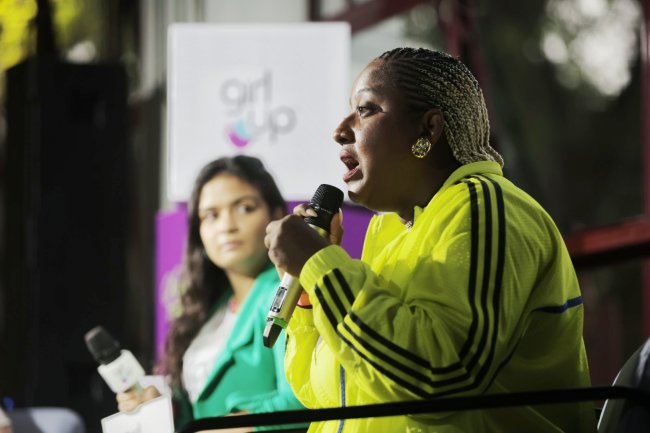 Dandara Pagu Mulher preta usa moletom amarelo e fala no microfone