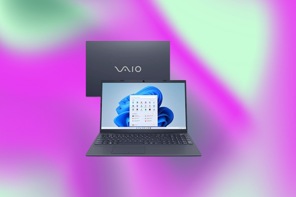 Imagem de um laptop cinza escuro em um fundo roxo e verde claro
