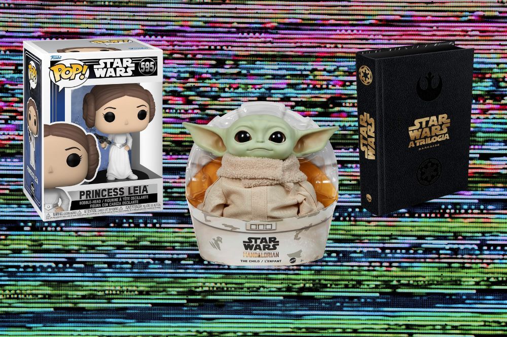 Funko Pop da Princesa Leia, boneco do Baby Yoda e livro da trilogia de Star Wars em um fundo com listras coloridas que imitam uma tela de televisão falhando