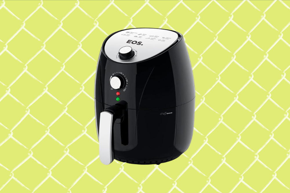 Imagem de uma air fryer preta com a parte de cima e o puxador cinza, em um fundo amarelo.