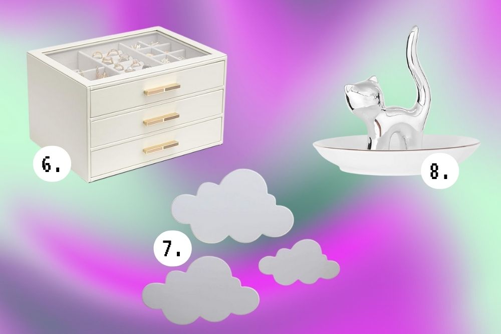 Ideias de decoração de quarto para quem é fã da Sabrina Carpenter Imagem de um porta-maquiagem branco, um gatinho de porcelana prata e um conjunto de nuvens de iluminária, em um fundo roxo e verde.