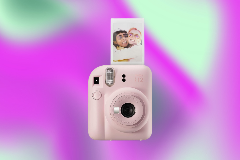 Imagem de uma máquina instax de foto rosa em um fundo roxo e verde.