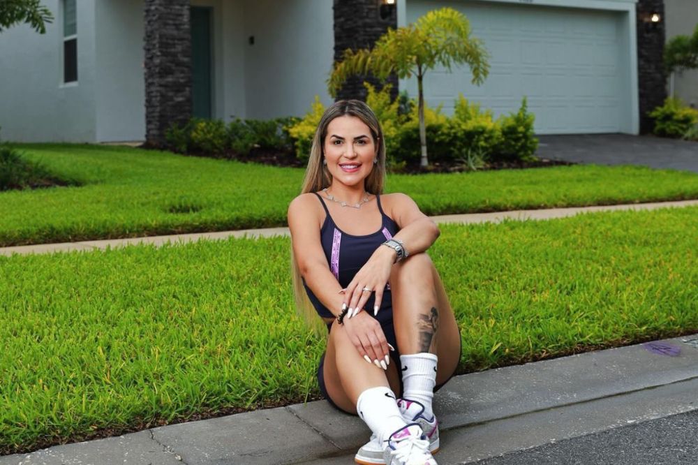 Imagem da influenciadora Deolane Bezerra, mulher branca e loira, sentada em um gramado.